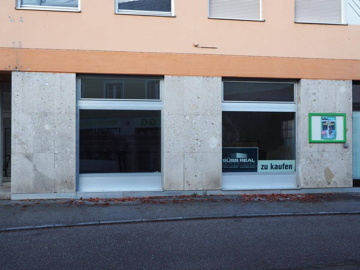 Fassade eines Gebäudes mit großen Schaufenstern und einer Werbetafel.