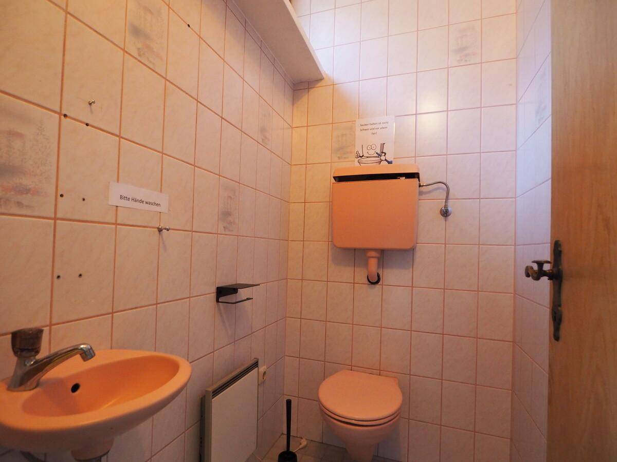 Kleines WC mit rosa Fliesen, passendem Waschbecken und Toilette.