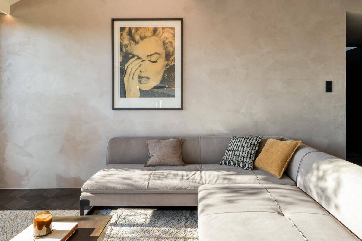 Gemütliche Sitzecke im Wohnzimmer mit modernem Sofa und Kunstwerk an der Wand.