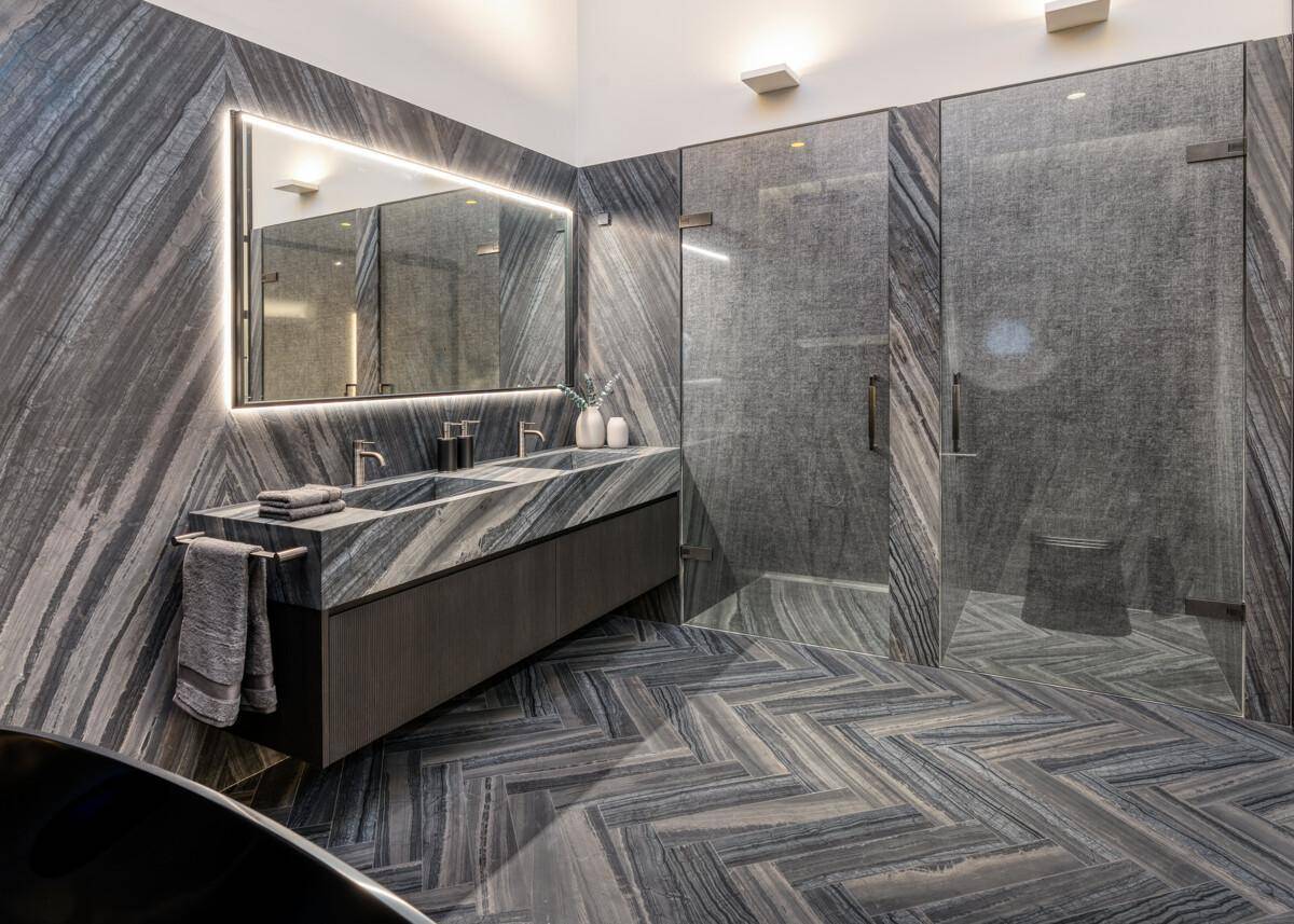 Modernes Badezimmer mit Doppelwaschbecken, beleuchtetem Spiegel und begehbarer Dusche.
