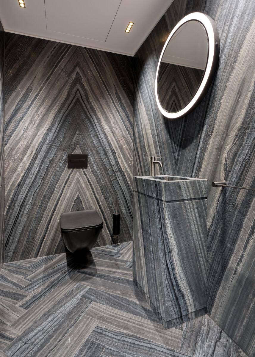 Stilvolles Gäste-WC mit Wand-WC, freistehendem Waschtisch und Marmorverkleidung.