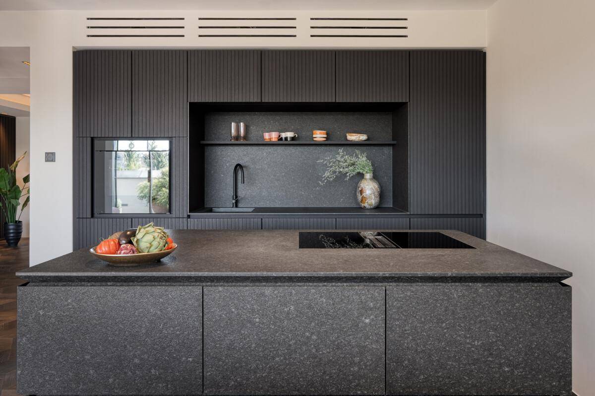 Moderne schwarze Küche mit Kochinsel, integrierten Geräten und dunkler Granit-Arbeitsplatte.