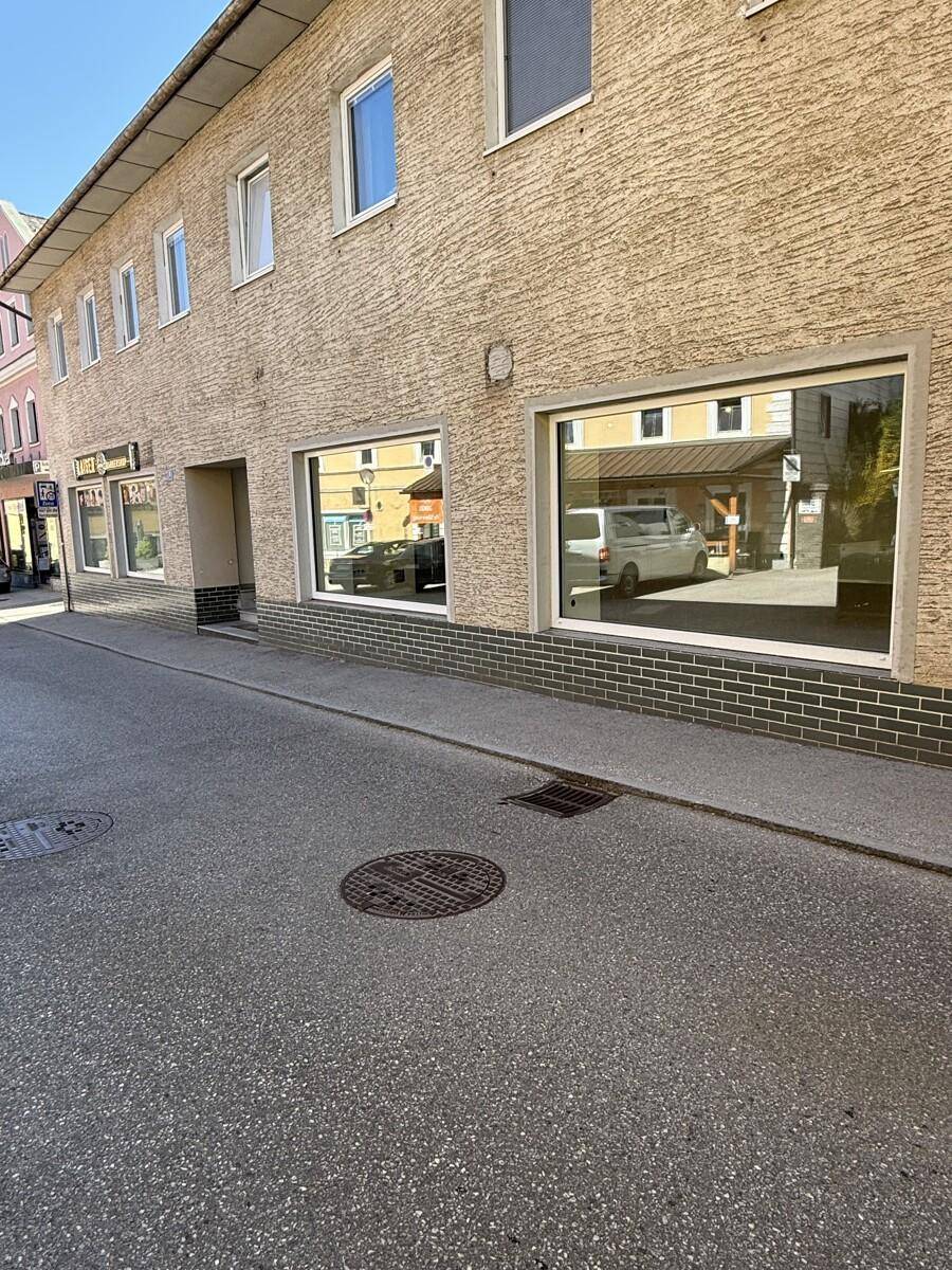 Fassade eines Gebäudes mit großen Schaufenstern im Erdgeschoss und darüberliegenden Wohnungen.
