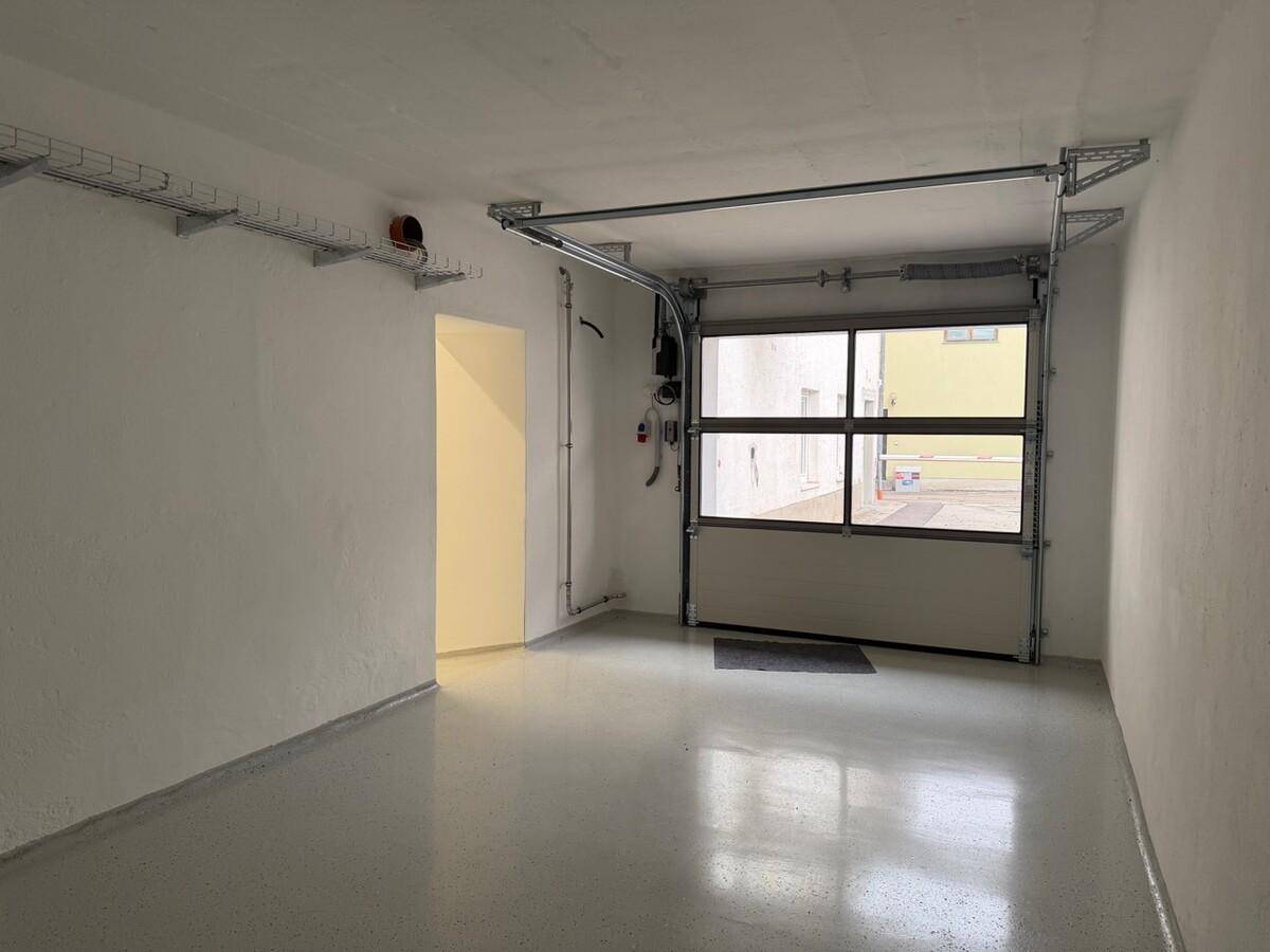 Geräumige Garage mit großem Garagentor, grauem Boden und weißen Wänden, bereit zur Nutzung.