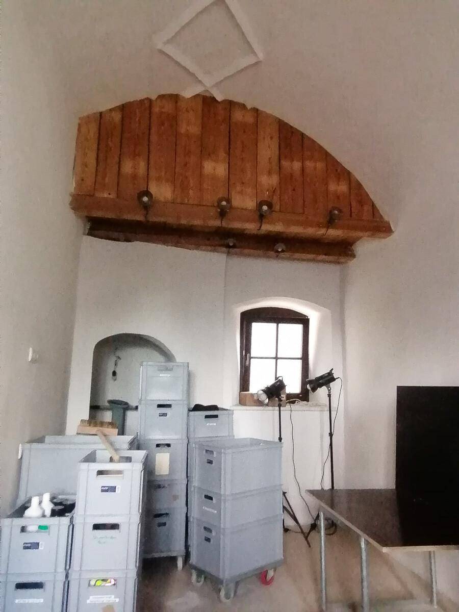Innenraum mit rustikaler Holzkonstruktion an der Decke und einem kleinen Fenster, genutzt als Lagerbereich.