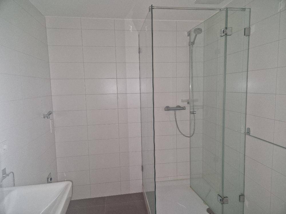 Modernes Badezimmer mit großer begehbarer Dusche und weißen Fliesen.