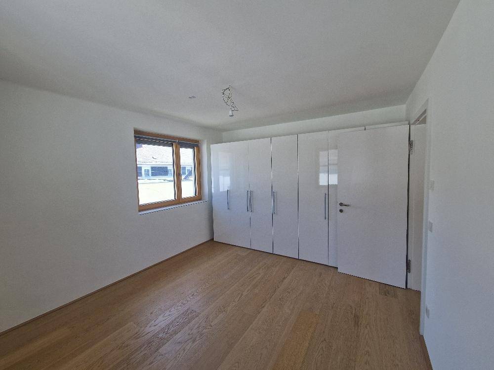 Schlafzimmer mit hellem Holzboden und großem, weißem Einbauschrank.