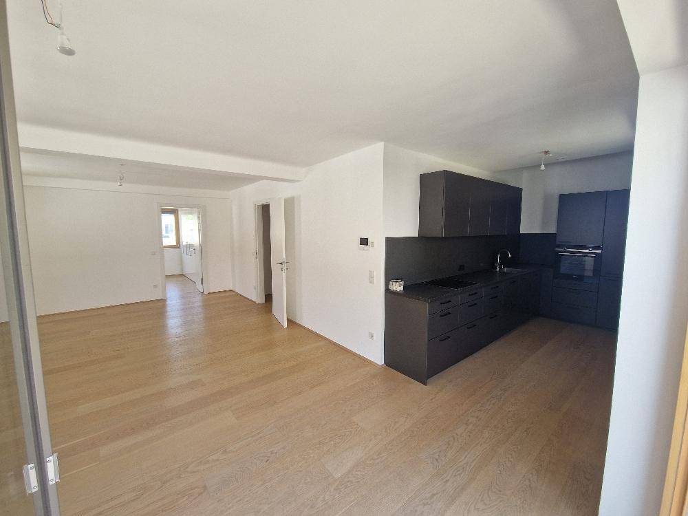 Offener Wohnbereich mit integrierter Küche und hellem Holzfußboden.
