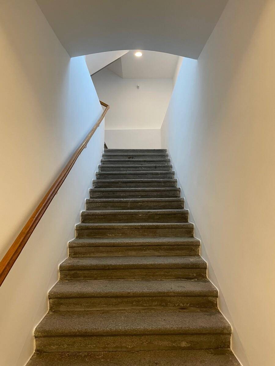 Treppenhaus mit Holzgeländer und Stufen, die nach oben führen.