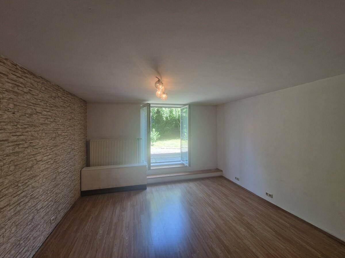 Geräumiges Wohnzimmer mit Laminatboden und einer strukturierten Wand, die einen Akzent setzt.