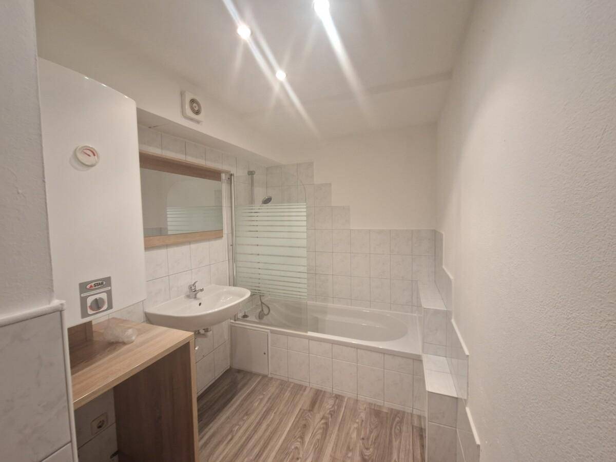Helles Badezimmer mit Badewanne, Waschbecken und Fliesenboden in einem funktionalen Design.