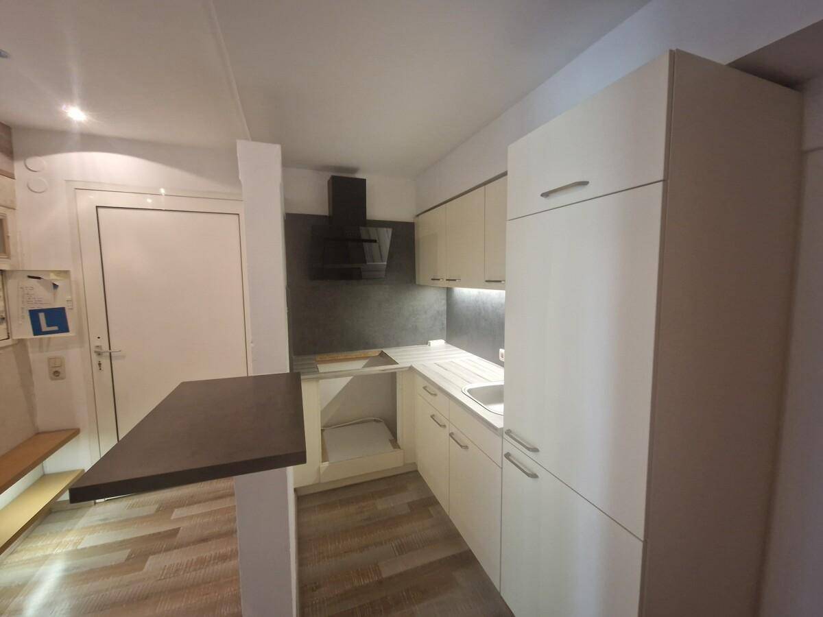 Moderne Einbauküche mit hellen Schränken, Dunstabzugshaube und einer praktischen Frühstücksbar.