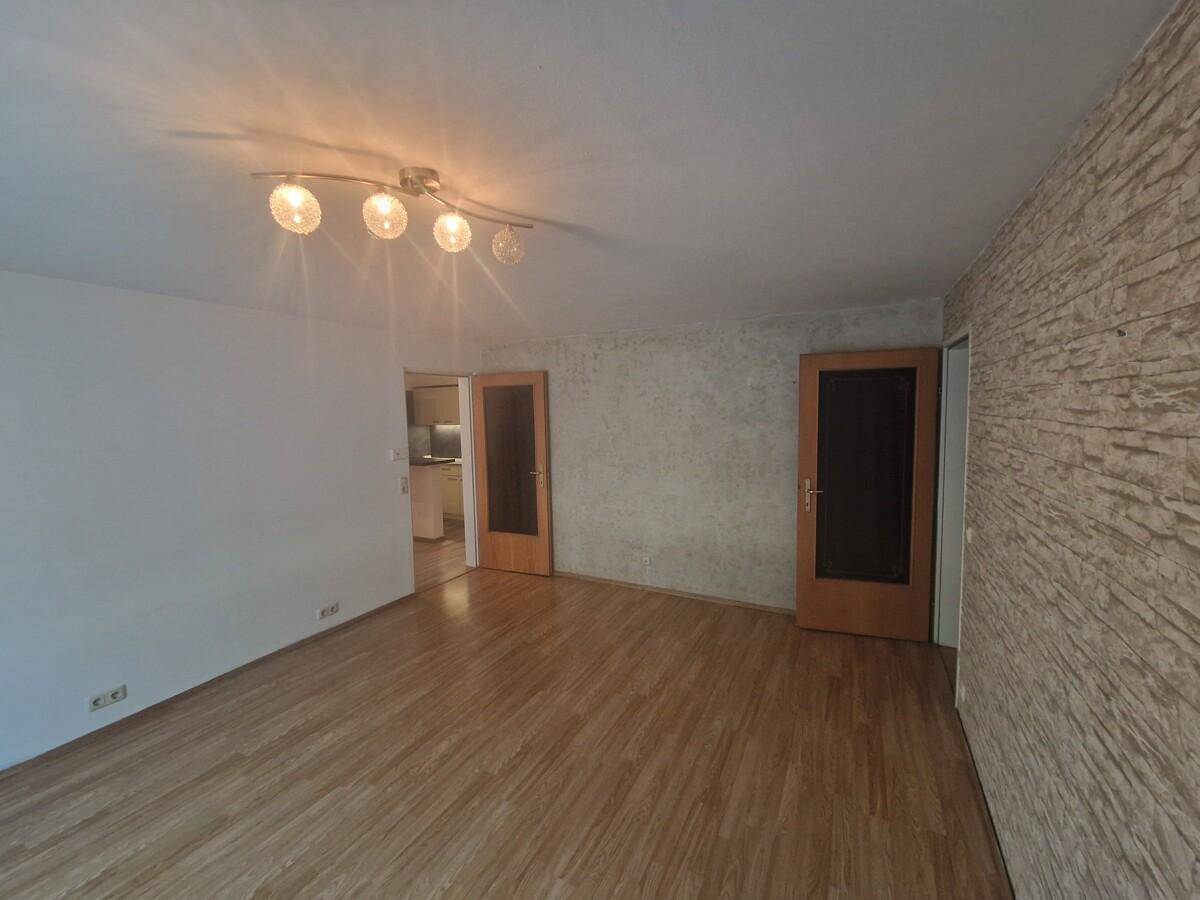 Wohnzimmer mit Laminatboden, strukturierten Wänden und Holztüren, die den Raum abgrenzen.
