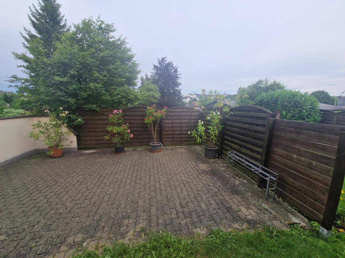 Gepflasterter Außenbereich mit Topfpflanzen und Holzzaun, ideal für eine kleine Terrasse.