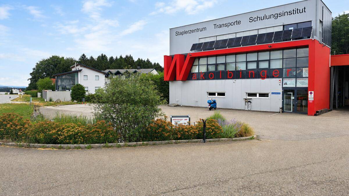 Weitläufige Außenansicht des Gewerbegebäudes mit umliegender Landschaft und weiteren Gebäuden im Hintergrund.