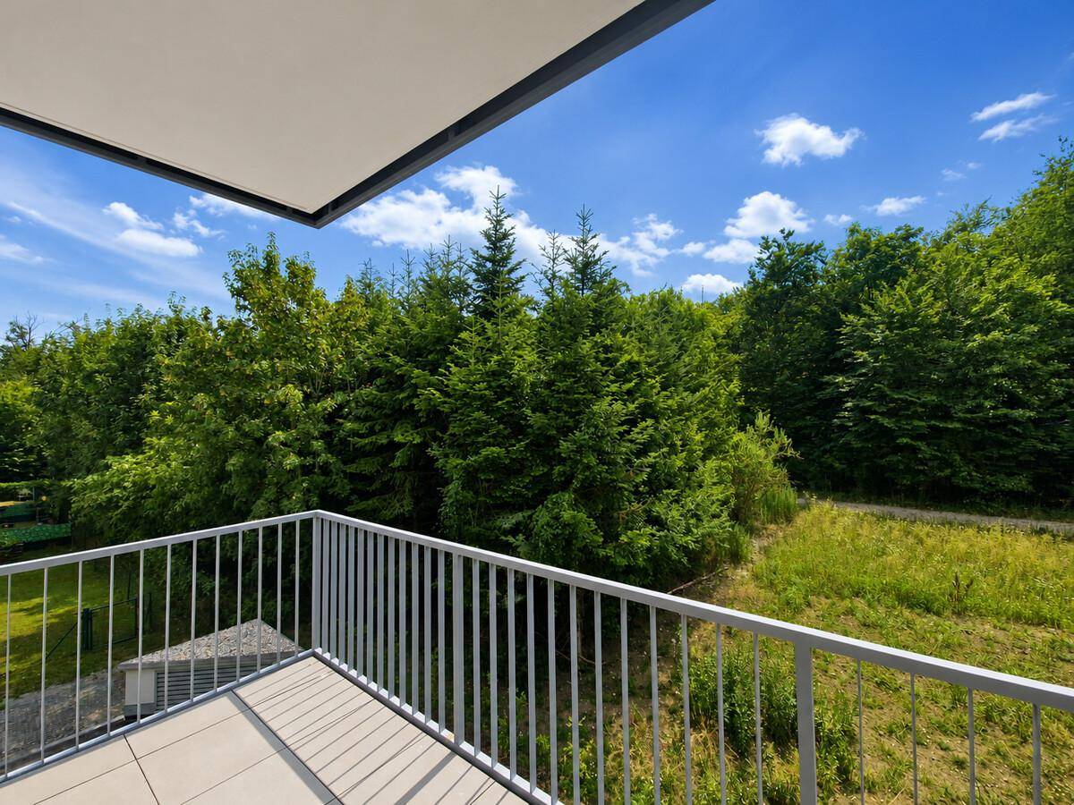 Heller Balkon mit moderner Brüstung und weitem Blick ins Grüne.