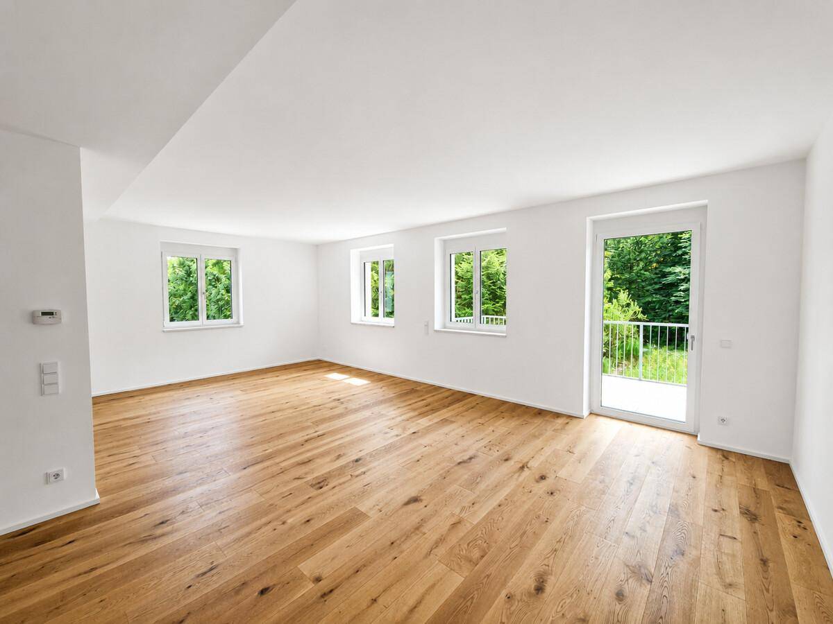 Großer, heller Raum mit Holzboden, vielen Fenstern und Balkonzugang.