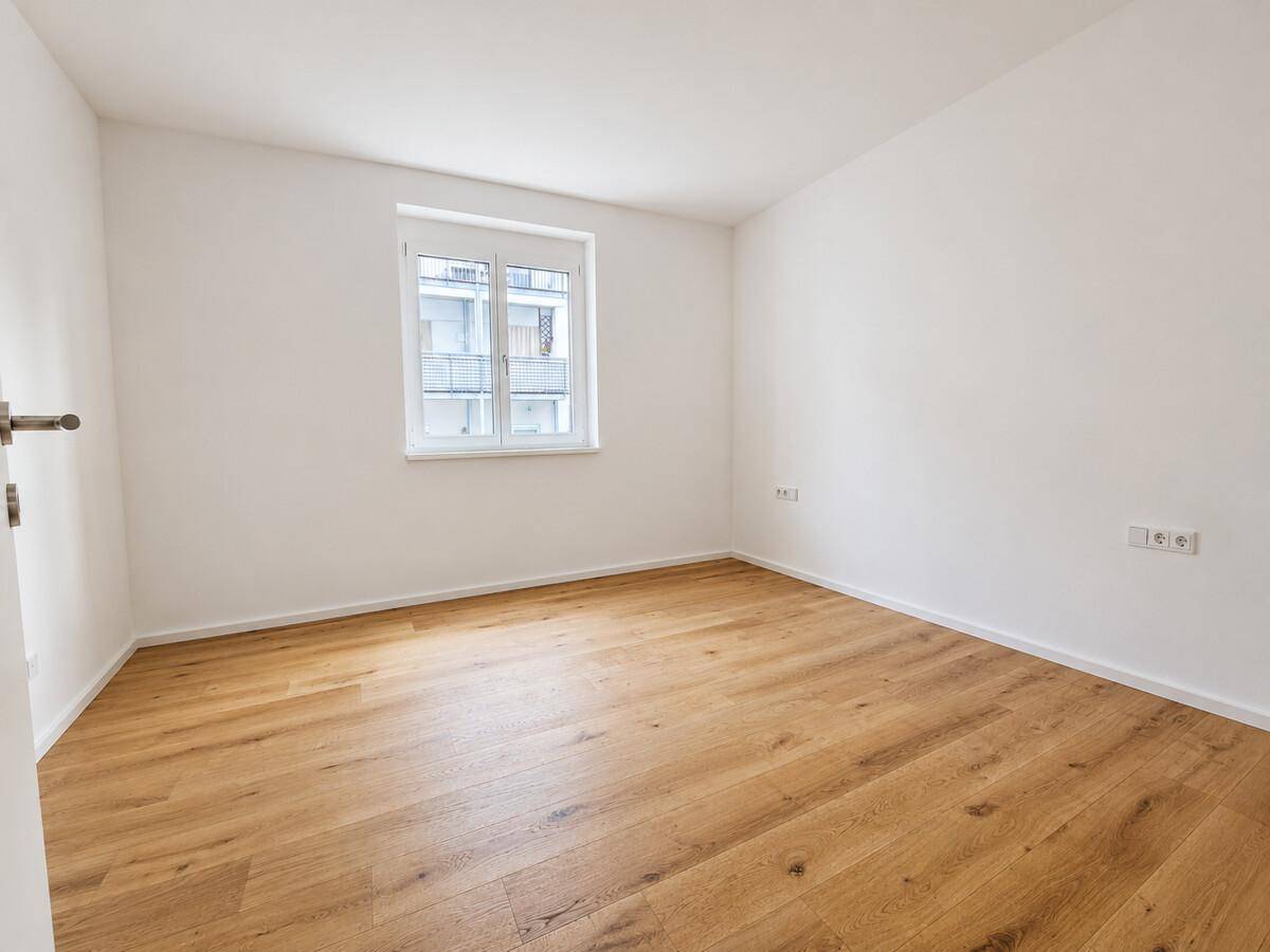 Heller Raum mit Holzboden und einem Fenster, bereit zur individuellen Gestaltung.