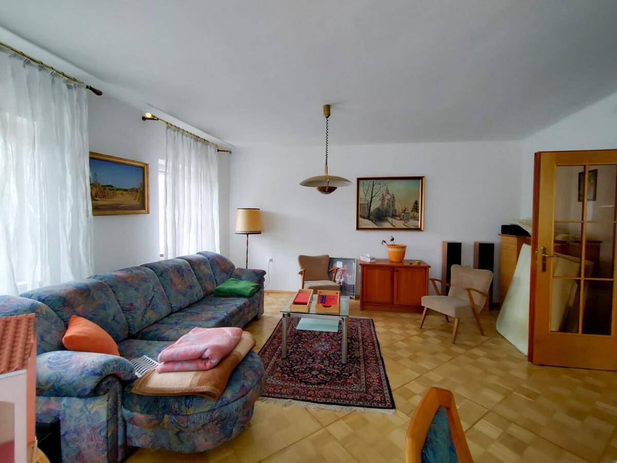Gemütliches Wohnzimmer mit Sofa, Teppich und hellem Parkettboden.