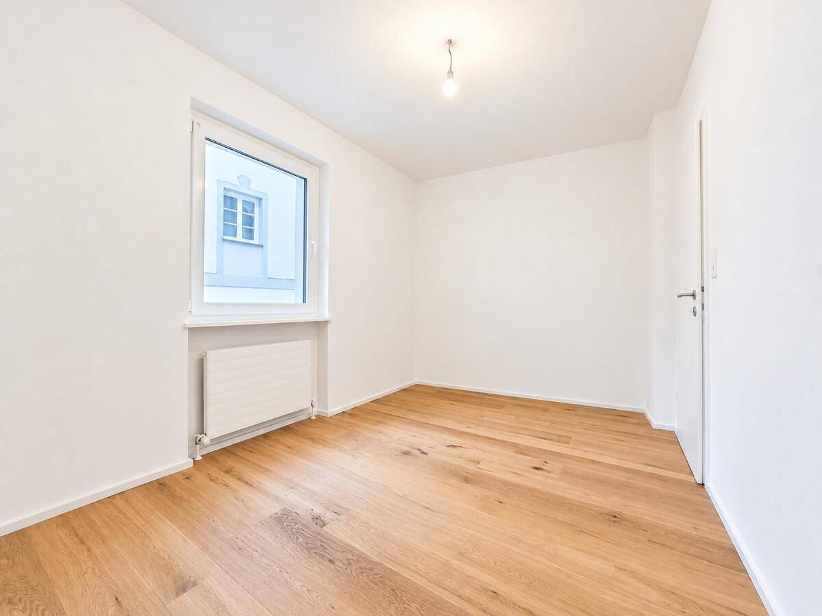 Leeres Zimmer mit Holzboden und einem Fenster, ideal als Schlaf- oder Kinderzimmer nutzbar.