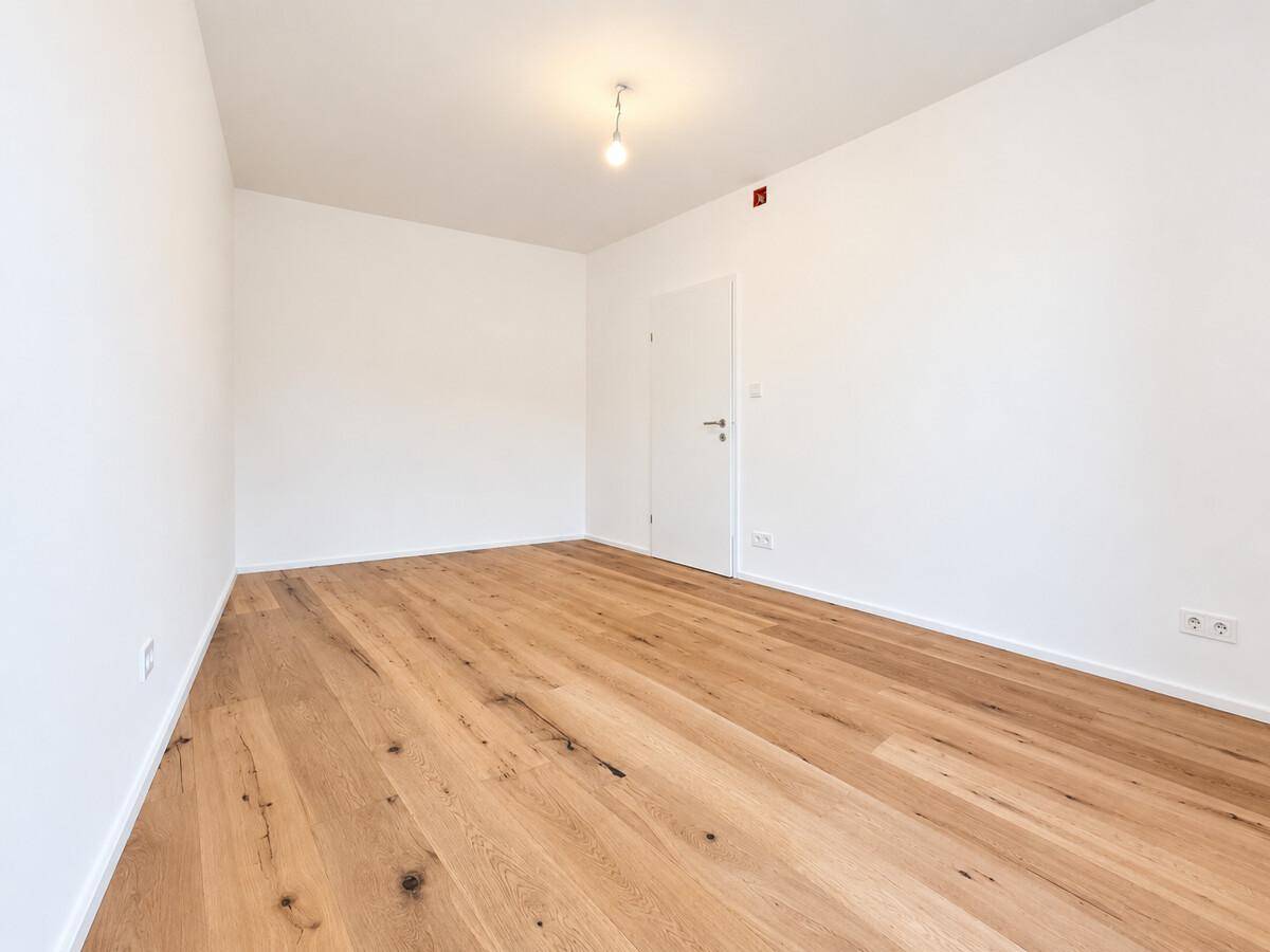 Leeres Zimmer mit Holzboden und einer Tür, ideal als Schlafzimmer oder Arbeitszimmer.