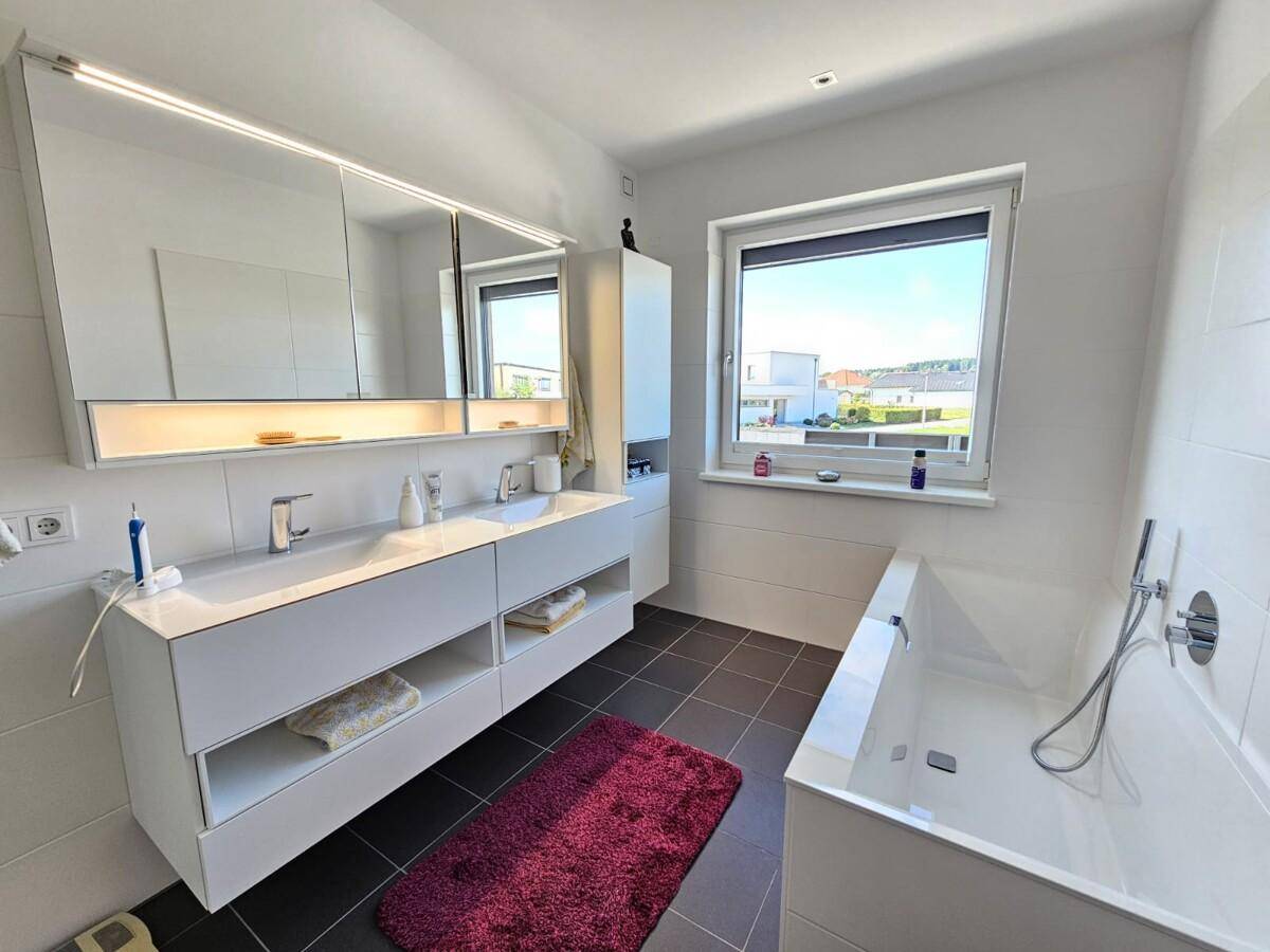 Helles Badezimmer mit Doppelwaschbecken, Badewanne und großem Spiegelschrank.