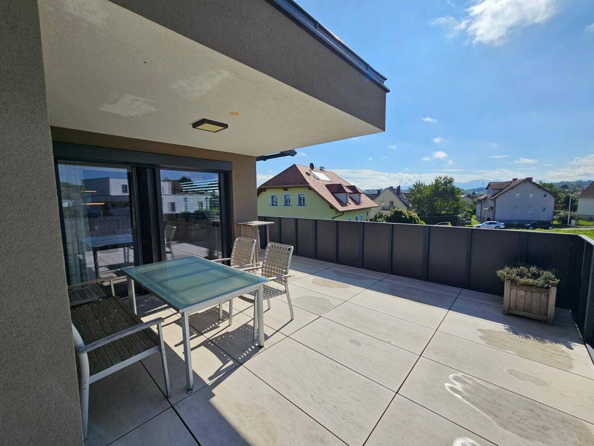 Helle Terrasse mit Sitzgelegenheiten und weitem Blick über die umliegende Wohngegend und Landschaft.