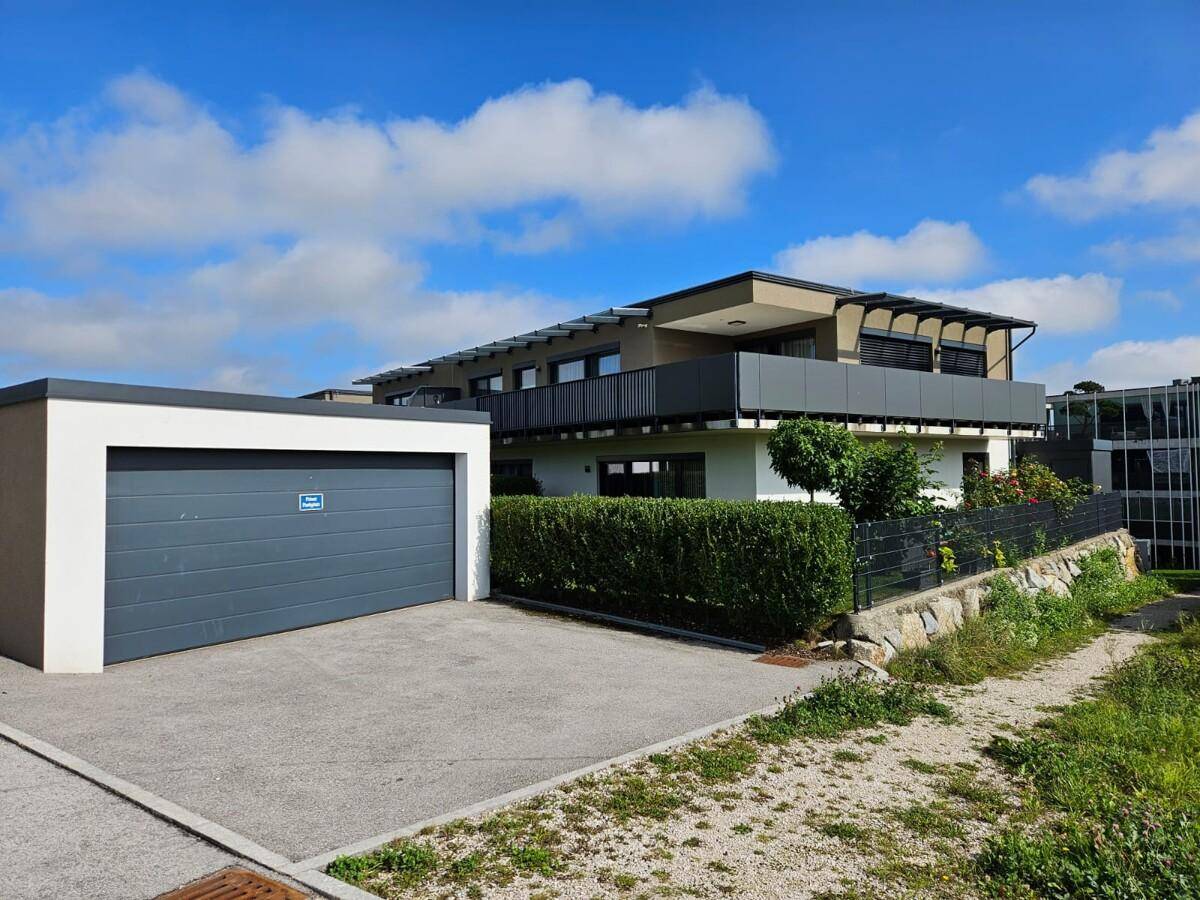 Modernes Gebäude mit Garage und gepflegter Hecke im Außenbereich.