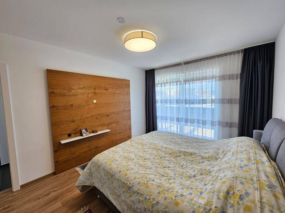 Gemütliches Schlafzimmer mit großem Bett, Holzwandverkleidung und Zugang zum Balkon.