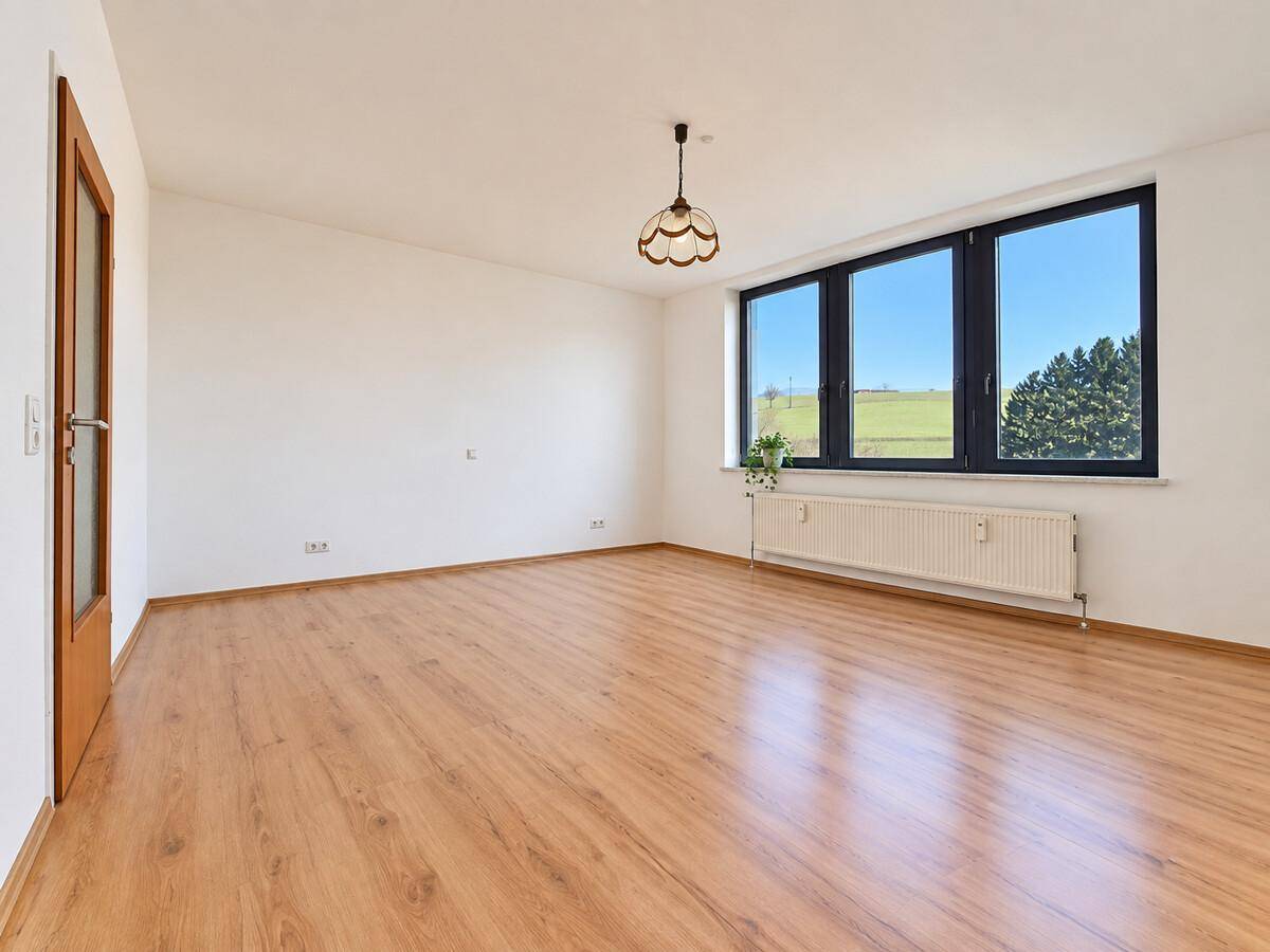 Helles Schlafzimmer mit Laminatboden, Fenster und Blick auf die umliegende Landschaft.
