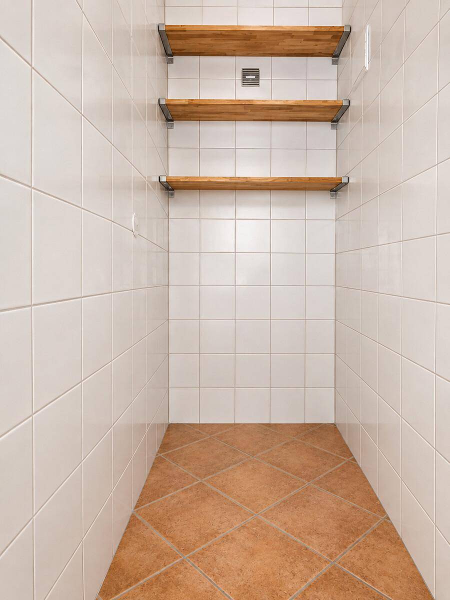 Praktischer Abstellraum mit Fliesenboden und drei Holzregalen für zusätzlichen Stauraum.