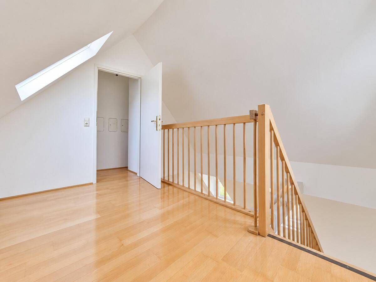 Offener Galeriebereich im Dachgeschoss mit Holzgeländer und Zugang zu einem weiteren Raum.