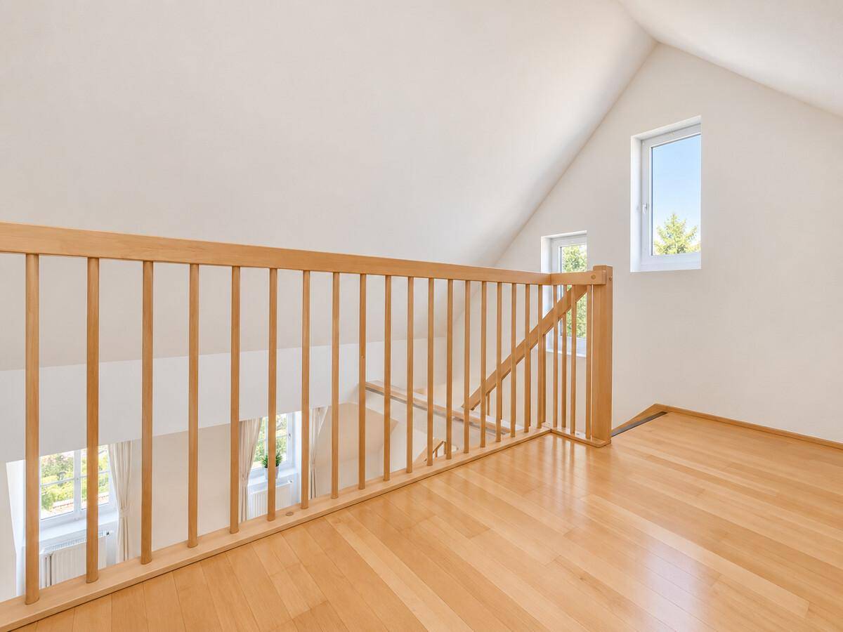 Helle Galerie im Dachgeschoss mit Holzgeländer und Blick auf die unteren Räume.