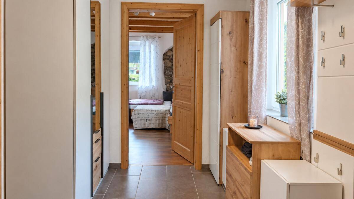 Heller Flur mit Holzdecke und Fliesenboden, der zu einem Schlafzimmer führt.