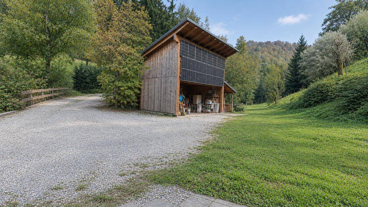 Rustikales Holzgebäude mit Photovoltaikanlage und überdachtem Bereich in ländlicher Umgebung.