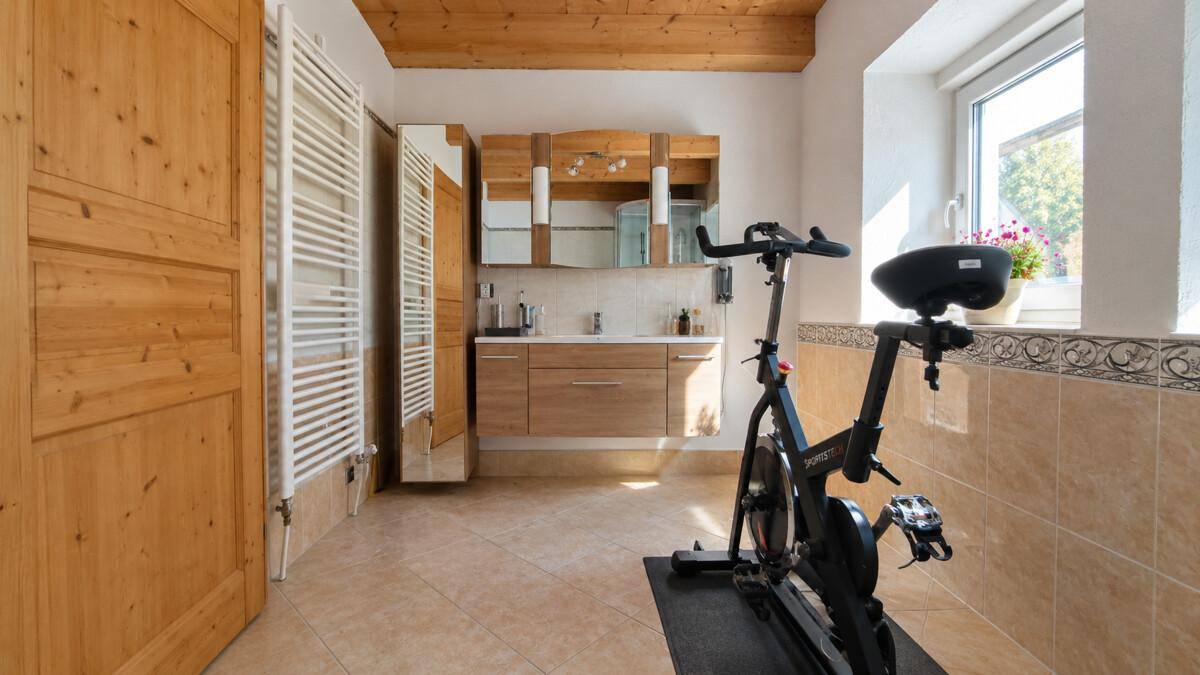 Geräumiges Badezimmer mit Holzdecke, beigefarbenen Fliesen und einem Doppelwaschtisch.