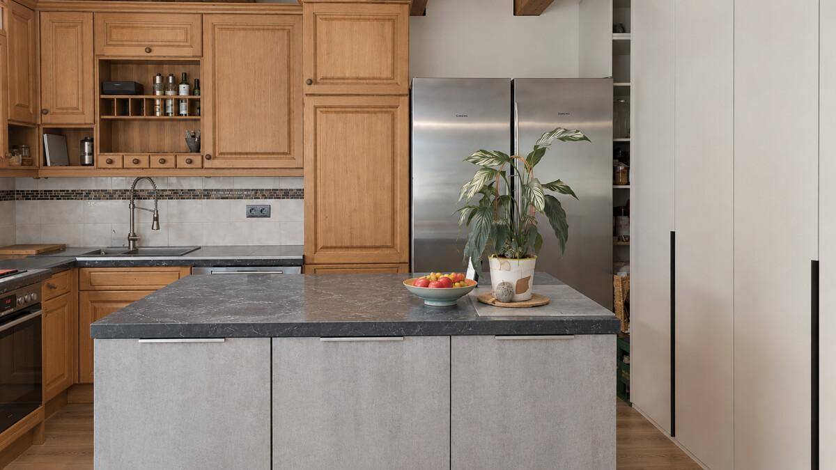Küche mit Holzschränken, moderner Kücheninsel und großem Kühlschrank.