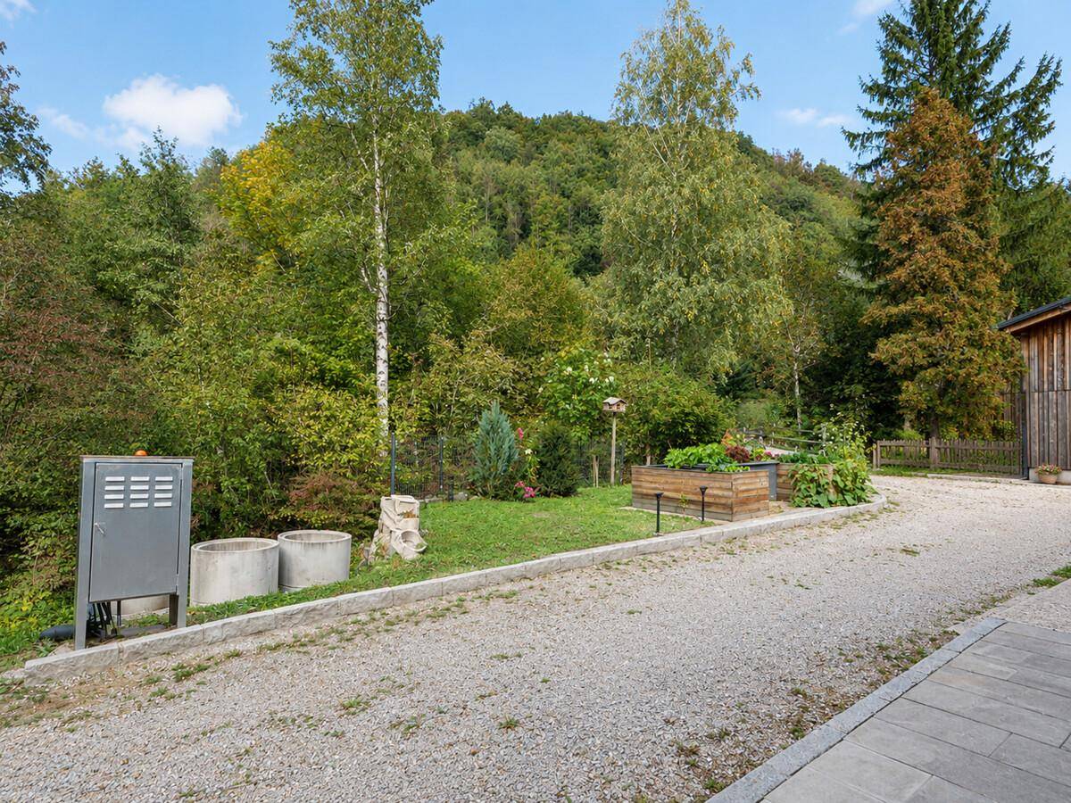 Kiesauffahrt mit erhöhtem Gemüsebeet und umgebender grüner Landschaft.
