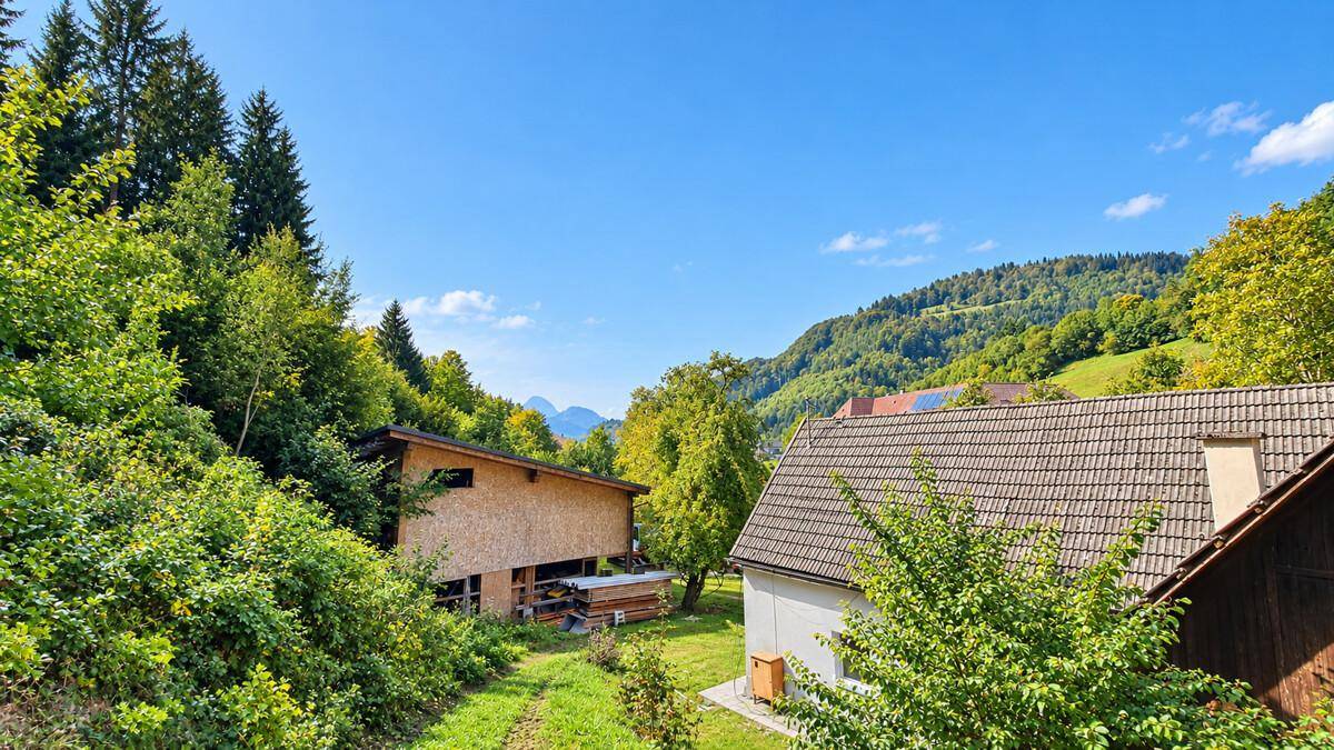 Panoramablick auf die ländliche Umgebung mit bewaldeten Bergen und einem weiteren Gebäude.