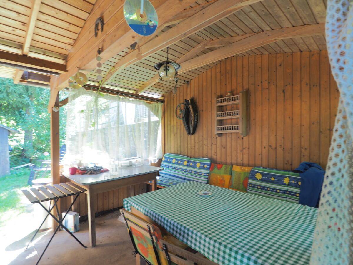 Gemütlicher, überdachter Holzpavillon mit Esstisch und Sitzbänken, ideal für entspannte Stunden im Freien.