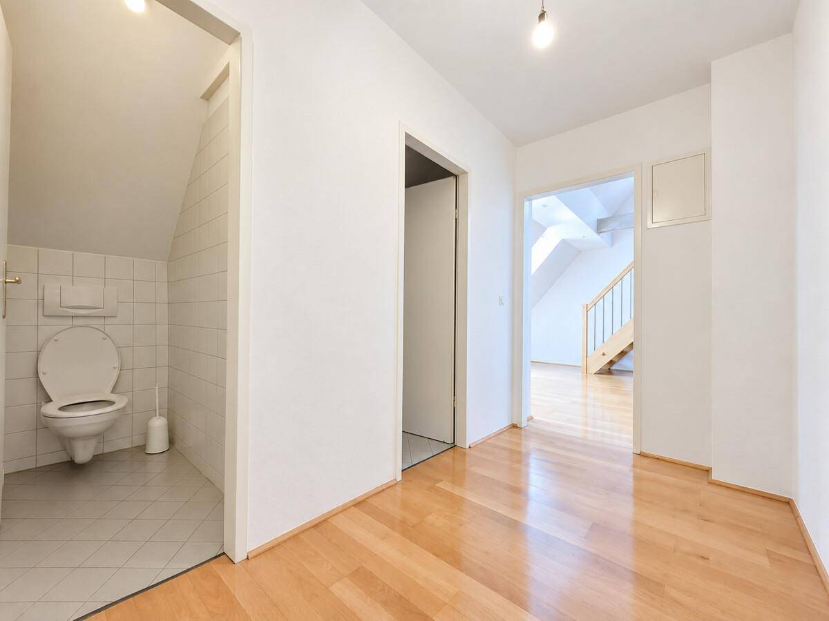 Heller Flur mit Parkettboden und Zugang zu einem WC unter der Dachschräge.
