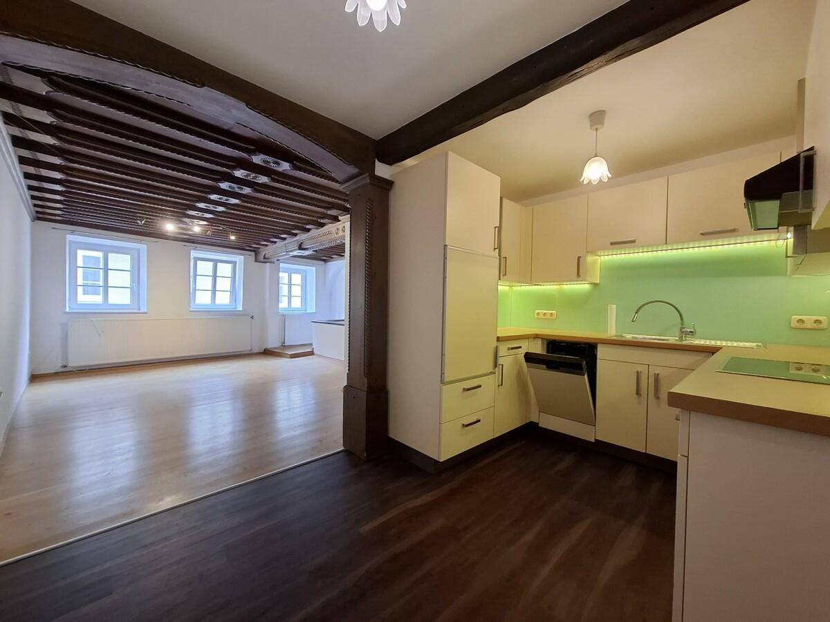 Moderne Einbauküche mit hellen Schränken und Blick in den angrenzenden Wohnbereich.