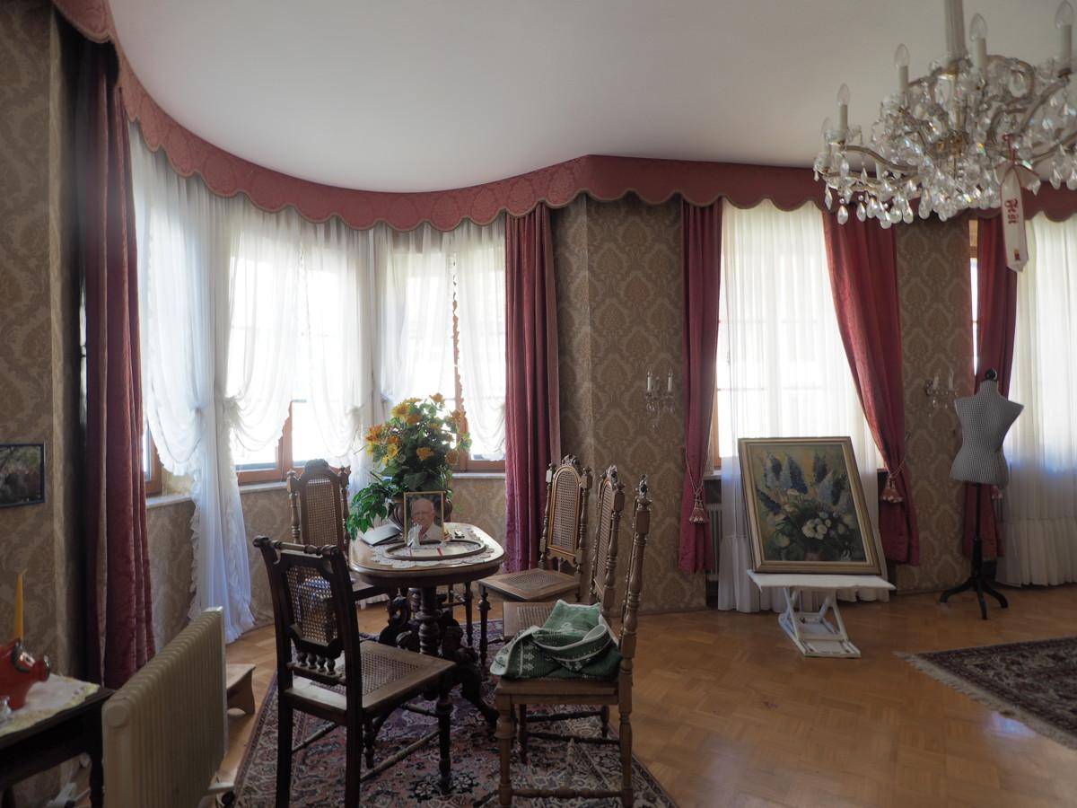 Helles Wohnzimmer im Vintage-Stil mit großen Fenstern und elegantem Kronleuchter.
