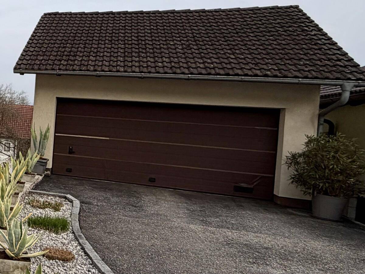 Doppelgarage mit braunem Tor und Zufahrt, Teil des Anwesens.