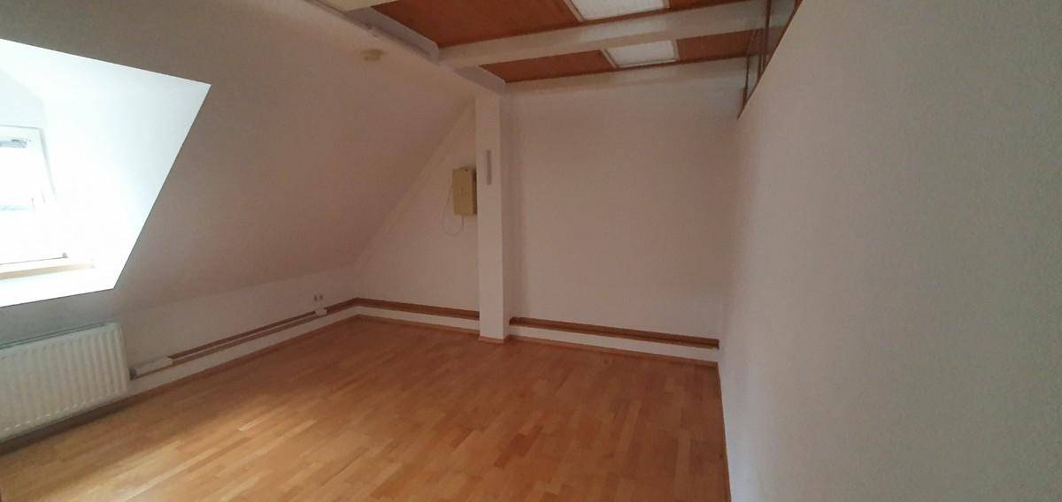 Helles Schlafzimmer im Dachgeschoss mit Holzboden und schrägem Dachfenster.