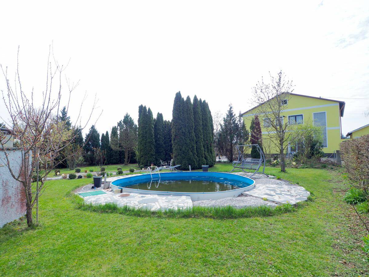 Weitläufiger Gartenbereich mit einem runden Aufstellpool und viel Grünfläche zum Entspannen.