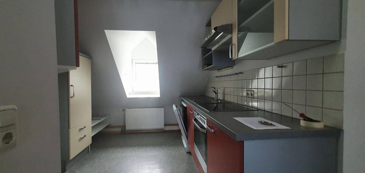 Funktionale Küche im Dachgeschoss mit Einbauschränken, Herd und Dachfenster.