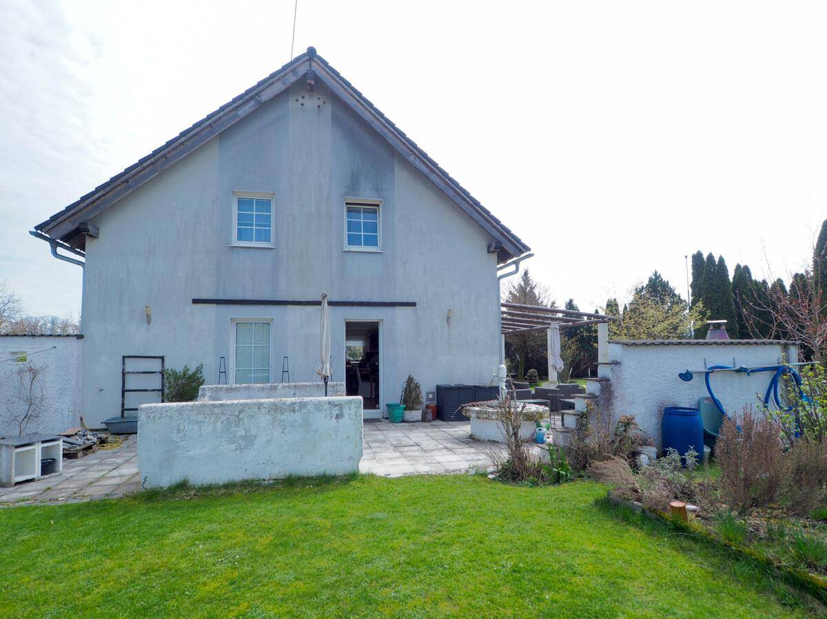 Seitenansicht des Hauses mit großer gepflasterter Terrasse und Zugang zum Garten.