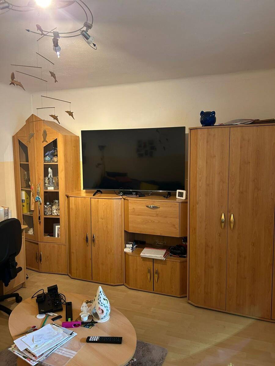 Wohnzimmer mit großer TV-Wand und Holzmöbeln, gemütlich eingerichtet.