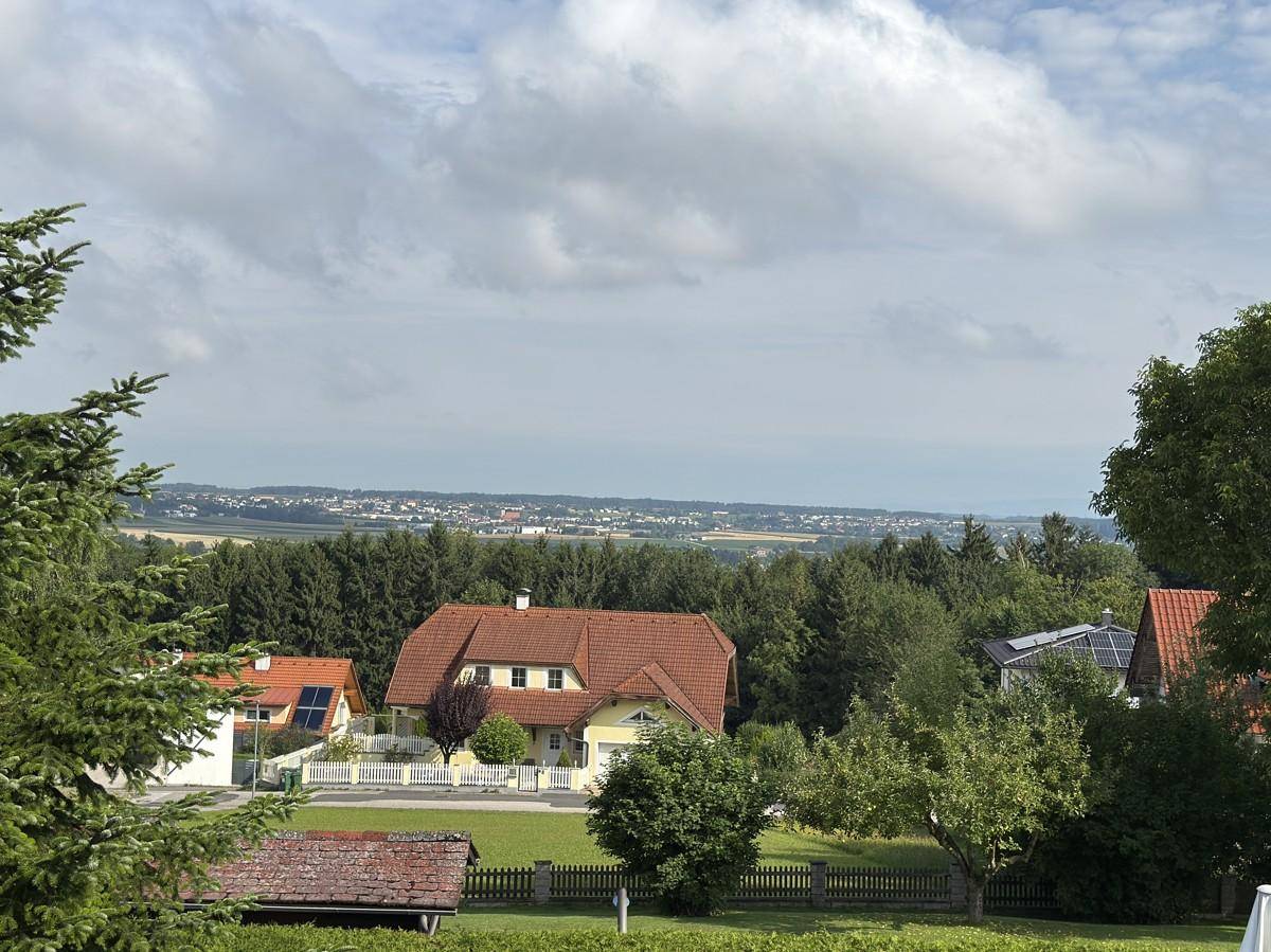 Panoramablick über eine Wohngegend mit roten Dächern und weitem Horizont bis zu einer Stadt.